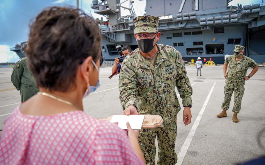 Guam Gov. Lou Leon Guerrero accepts a commemorative plaque from then-Joint Region Marianas commander Rear Adm. John Menoni, at Naval Base Guam, June 4, 2020, as the USS Theodore Roosevelt prepares to depart the island. 