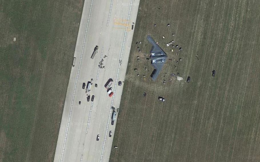 A satellite image screenshot shows a B-2 Spirit bomber, known as the Spirit of Georgia, surrounded by first responders and maintenance personnel in the grass off the flight line at Whiteman Air Force Base, Missouri, Sept. 14, 2021. The stealth bomber suffered an in-flight malfunction due to faulty landing gear springs and skidded off the runway.