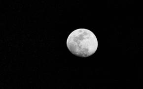 A mostly full moon is seen against a black sky.