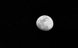 A mostly full moon is seen against a black sky.