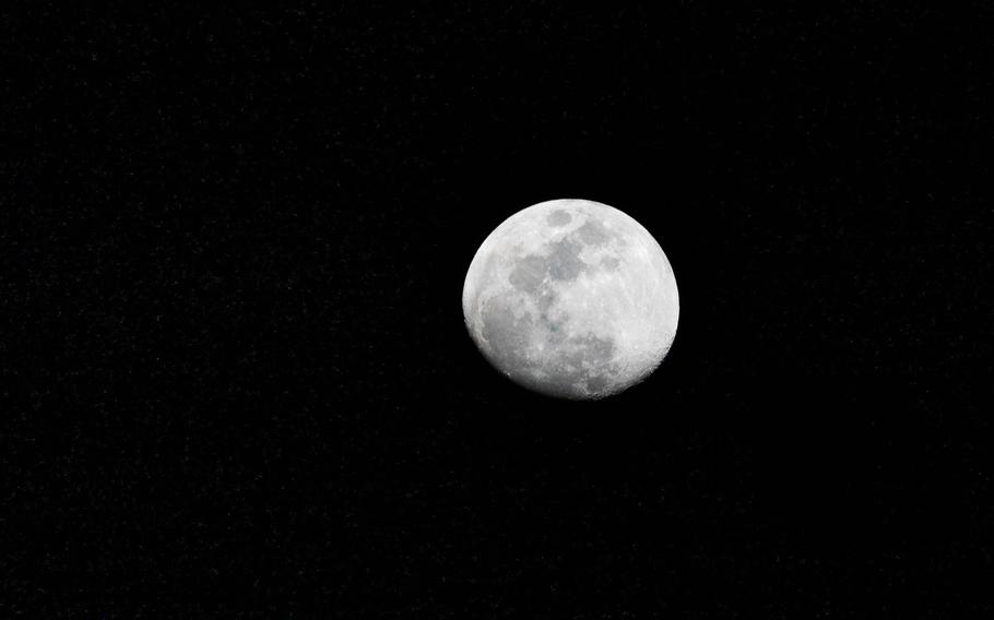 A mostly full moon is seen against a black sky.