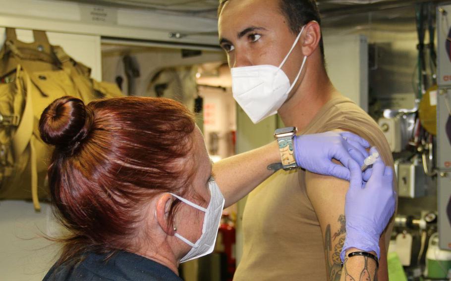 Aviation Ordnanceman 2nd Class Michael Stender receives a coronavirus booster shot from Tiffany Salveson, a corpsman assigned to the USS Milwaukee at Naval Station Guantanamo Bay, Cuba, on Dec. 28, 2021.  The USS Milwaukee returned to sea Monday after a coronavirus outbreak among crewmembers halted the ship’s departure from a port visit in Cuba, according to the Navy.