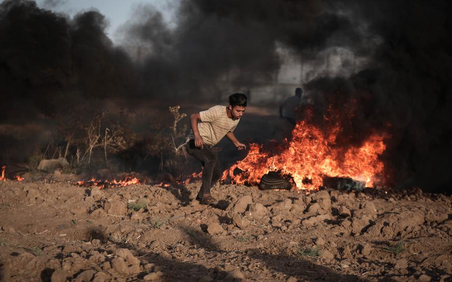 A Palestinian demonstrator drags burning rubber tires toward the border fence east of Gaza City on Friday, Sept. 15, 2023.