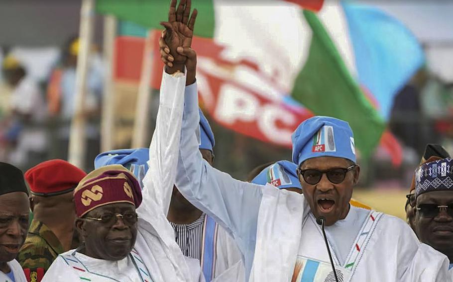 A video screen grab shows Nigerian President Muhammadu Buhari holding up the hand of candidate Bola Ahmed Tinubu.