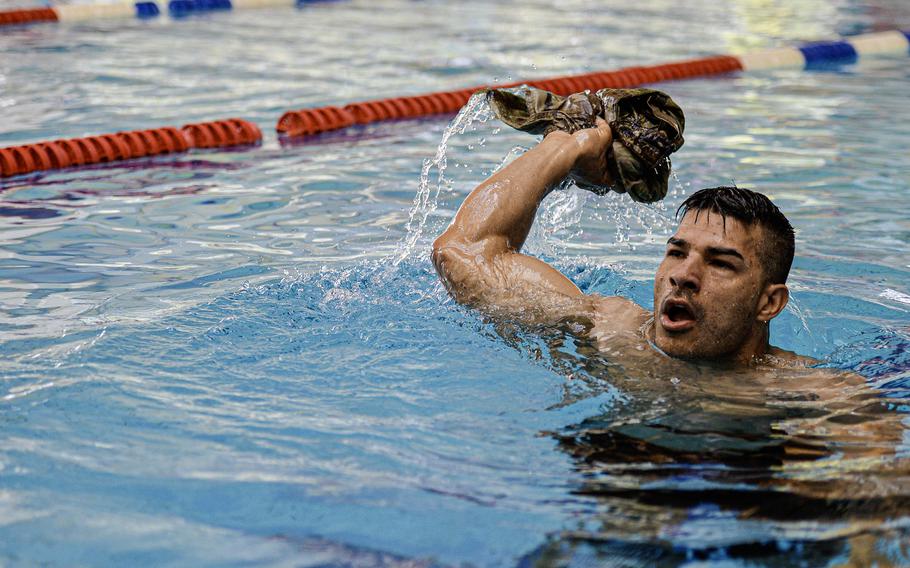Army Staff Sgt. Francisco Laporte, a corrections and detentions specialist, throws his uniform top while treading water, a requirement of the swim portion of the German Armed Forces Badge for Military Proficiency at Ramstein Air Base, Germany, April 22, 2024.