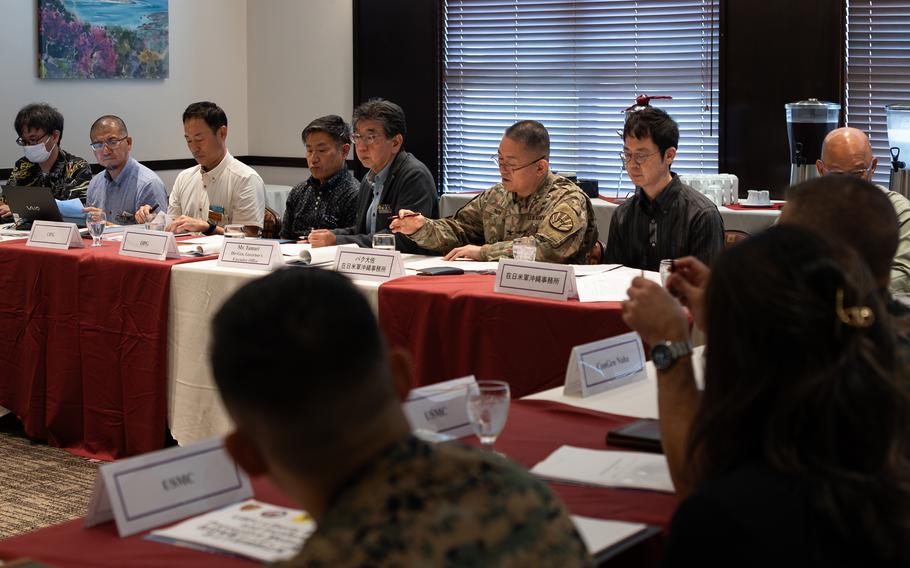 A U.S. soldier sits at a table and speaks with Japanese officials.