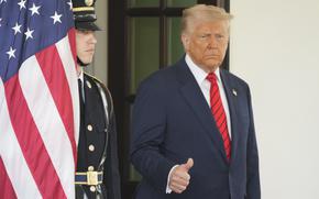 President Trump with a slightly raised hand that appears to be giving a thumbs up.