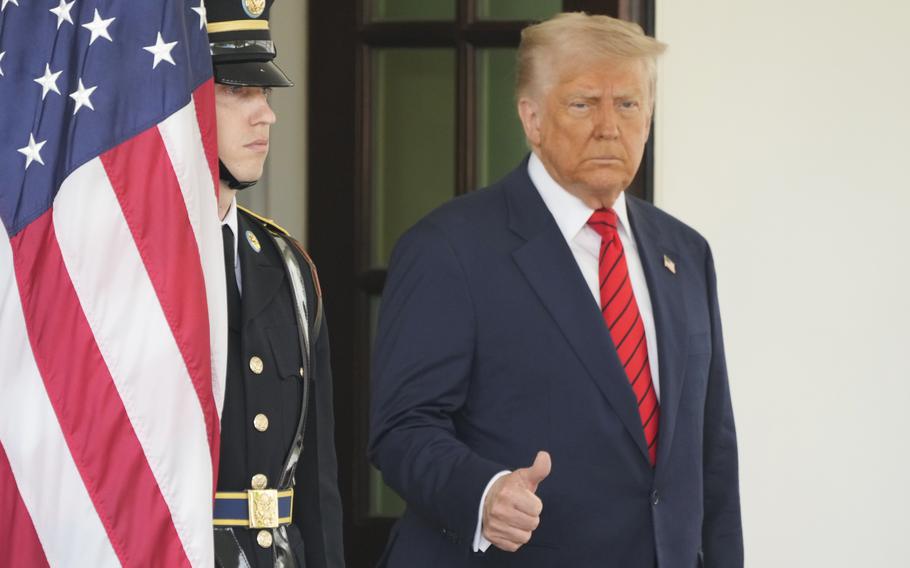 President Trump with a slightly raised hand that appears to be giving a thumbs up.