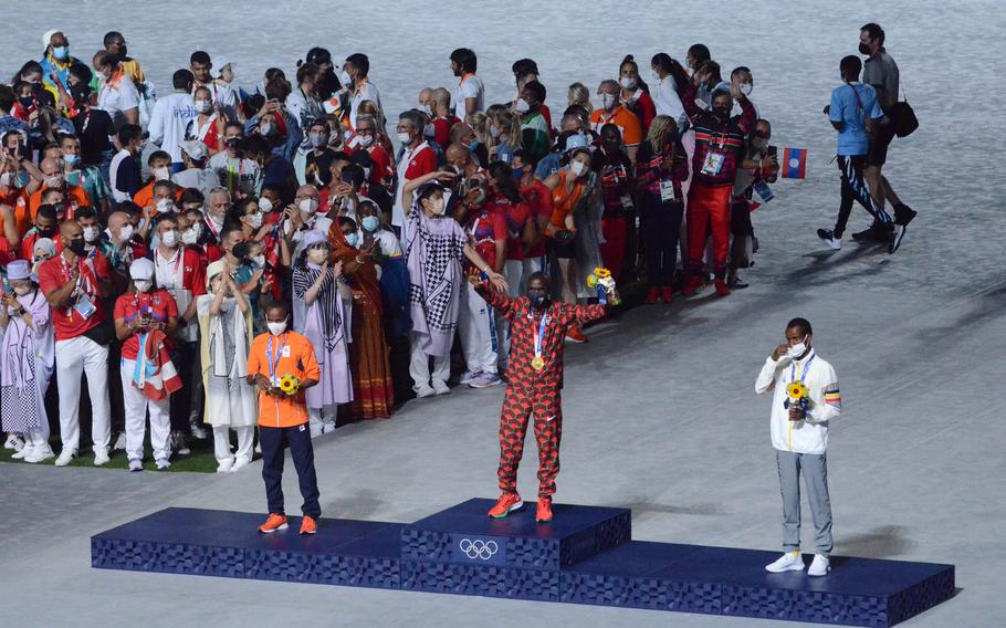 Kenya marathon runner Eliud Kipchoge celebrates after receiving his gold medal during the closing ceremony of the Tokyo Olympics, Sunday, Aug. 8, 2021. 