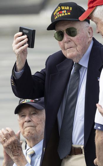 Veteran Jeffrey Donahue holds up a Greatest Generation coin during the 20th anniversary celebration of the National World War II Memorial in Washington, D.C., May 25, 2024.
