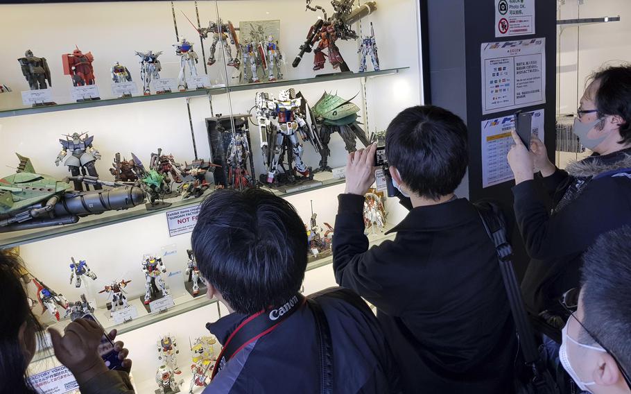 Visitors take photos of Gundam models at the Gundam Factory in Yokohama, Japan.