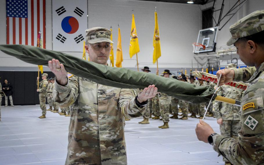 The commander of 2nd Stryker Brigade Combat Team, Col. Keith Benedict, left, helps case the colors during an authority transfer ceremony at Hanson Field House on Camp Casey, South Korea, Feb. 29, 2024. 