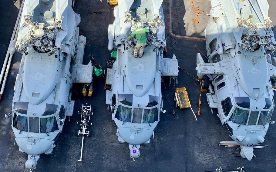 Maintenance crew members work on helicopters on the deck of the aircraft carrier USS Dwight D. Eisenhower on March 20, 2024.