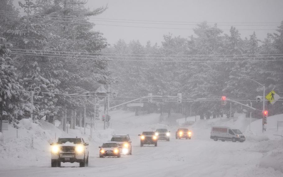 Vehicles drive as snow falls during another winter storm in the Sierra Nevada mountains on March 10, 2023, in Mammoth Lakes, Calif. 