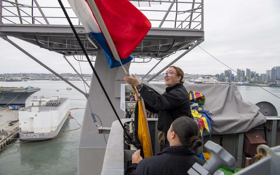 Seaman Gabriella Pantaleo hoists signal flags as the aircraft carrier USS Nimitz gets underway Oct. 2, 2022, in Coronado, Calif.