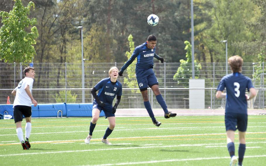 Black Forest Academy defender Samuel Yakubu heads the ball during a match against AFNORTH on April 20, 2024, at Ramstein High School on Ramstein Air Base, Germany. Following the play, from left, are Lion forward Michael Teichl and Falcon defender Timothy Sivonen.