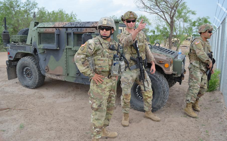 Texas National Guard Capt. Mario Cervantes, left, commander of Alpha Battery of Task Force Eagle in Eagle Pass, Texas, checks with members of his unit about activity along the Rio Grande’s shoreline on May 23. The troops are part of a state-sponsored border security mission known as Operation Lone Star.