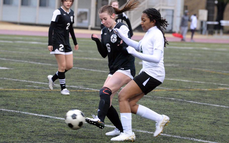 Robert D. Edgren’s Nia Tyler and Zama’s Lainey Felt try to play the ball during Friday’s DODEA-Japan season-opening soccer match. The Trojans won 5-1.