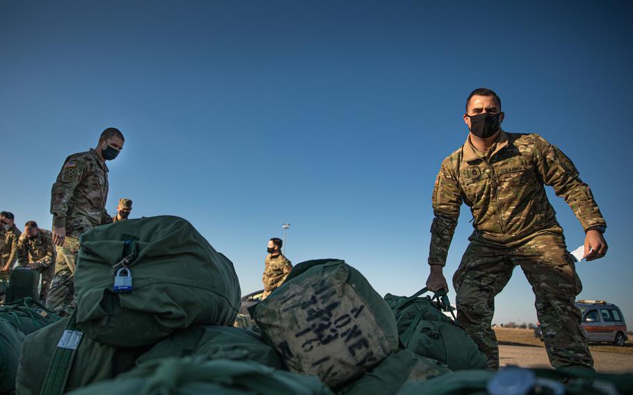 A soldier assigned to the 1st Infantry Division picks up his duffel bag after arriving in Poland on Feb. 28, 2022. There are now 100,000 U.S. troops in Europe, the largest number since 2005.