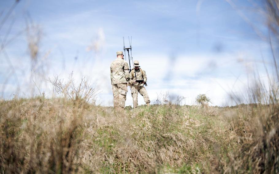 Two US Army soldiers talking to each other in a field.