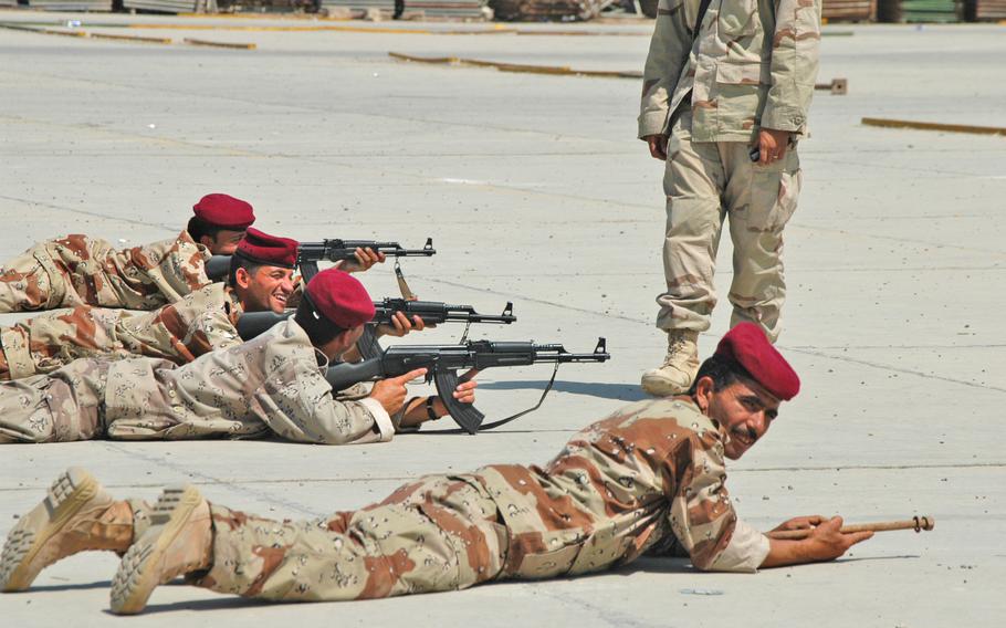 Iraqi soldiers rest during a "bounding" exercise at Camp Independence. The exercise teaches the soldiers how to advance or retreat in groups of two, with one group protecting the other with gunfire while moving. No ammunition was used in the drill, and one soldier uses a wooden stick in place of a rifle.