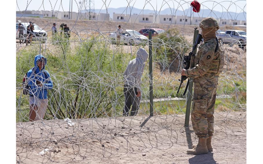 People look across the border from Mexico at the Texas Army National Guard soldiers with the governors self-styled Texas Tactical Border Force, during Operation Lone Star Task Force West, May 11, 2023, near El Paso, Texas. 