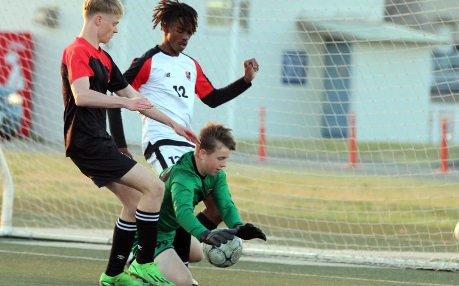 Nile C. Kinnick goalkeeper Aiden Talbot smothers the ball in front of Yokohama International's Cameron Maine and Red Devils teammate Mykhi Russell during Wednesday's boys soccer match. Kinnick won 4-2.