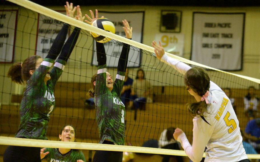 Kadena's Morgan Sayers spikes against the double block by Kubasaki's Grace Berrens and Adria Lockhart during Tuesday's DODEA-Okinawa volleyball match. The Dragons won in four sets.