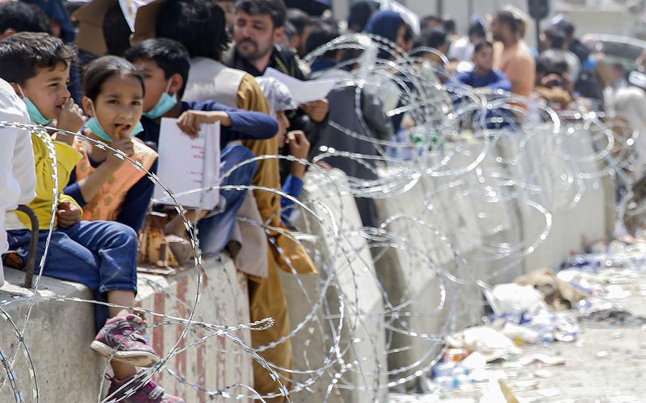 Afghans line a wall at Hamid Karzai International Airport, hoping to be evacuated from Afghanistan, Aug. 20, 2021. Mental health and veterans groups say they've seen an increase in the need for services among volunteers who tried to help Afghans evacuate, sometimes unsuccessfully. 