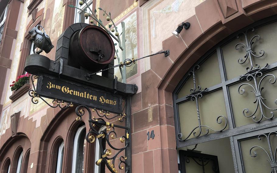 Apples, a barrel and a bembel, the pitcher apple wine is often served from, hang above the door on Diesterwegstrasse to the popular apple wine tavern Zum Gemalten Haus. Its main entrance is on Schweizerstrasse.