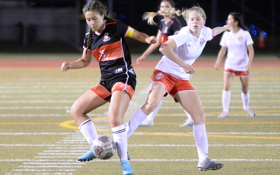 Nile C. Kinnick's Bree Withers and E.J. King's Maliwan Schinker scuffle for the ball during Friday's DODEA-Japan girls soccer match. The Red Devils won 2-1.