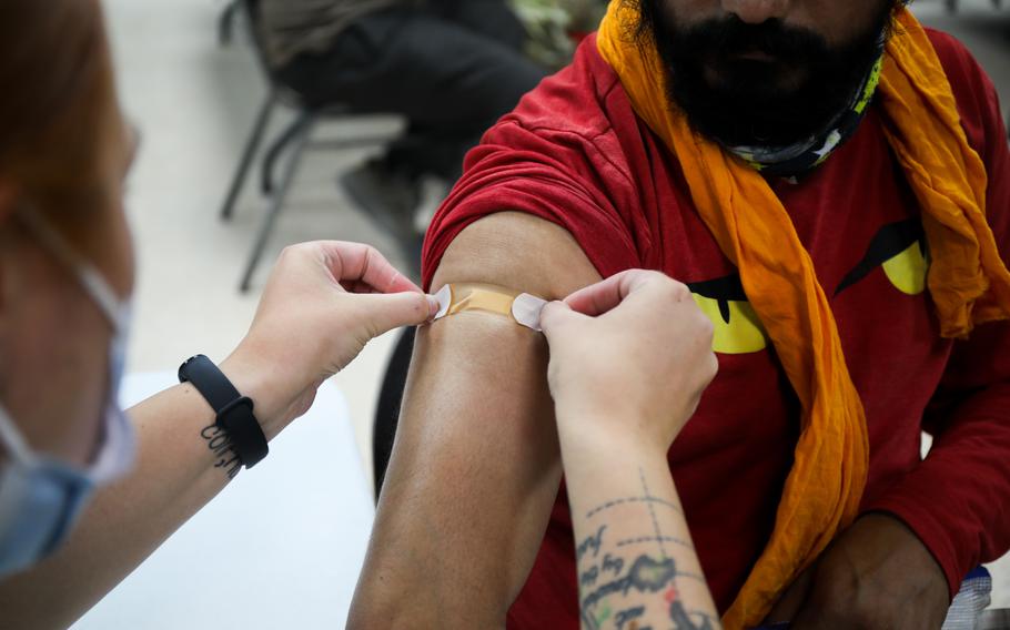 Spc. Samantha Stoler, combat medic, 3rd Infantry Division Sustainment Brigade, places a bandage on a contractor during a COVID-19 vaccination shot event at Camp Arifjan, Kuwait, July 12, 2021. 