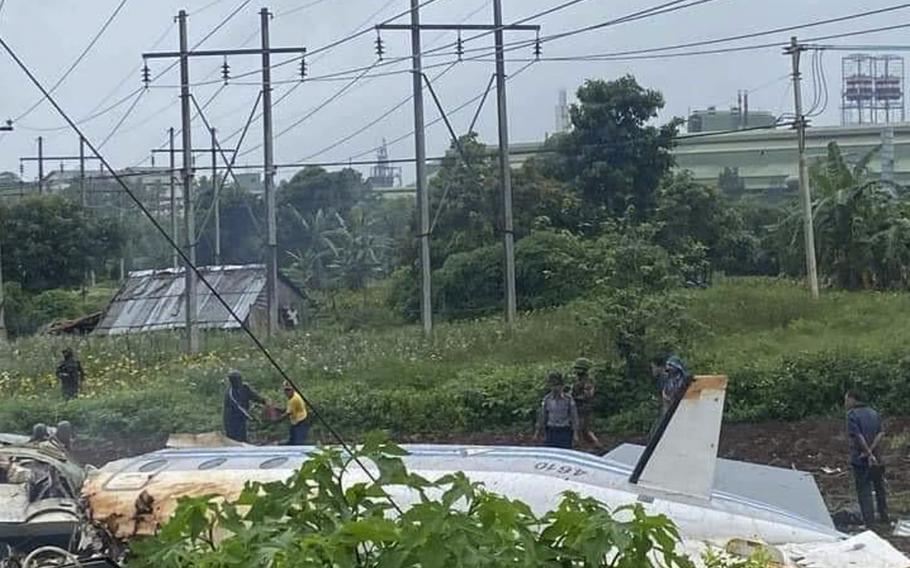 Military and locals stand beside the wreckage of a Myanmar Air Force Beechcraft 1900 that crashed in Pyin Oo Lwin, Mandalay, Myanmar on Thursday June 10, 2021. Twelve of the 14 passengers were killed, according to state media.