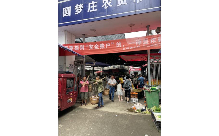 Shoppers at the entrance to Yuanmengzhuang market in China's Enshi city. A chicken vendor recalled live wildlife being sold there as recently as late 2019. In March 2020, local authorities banned meat and vegetable stores and other mobile stalls from operating outside the designated market area. 