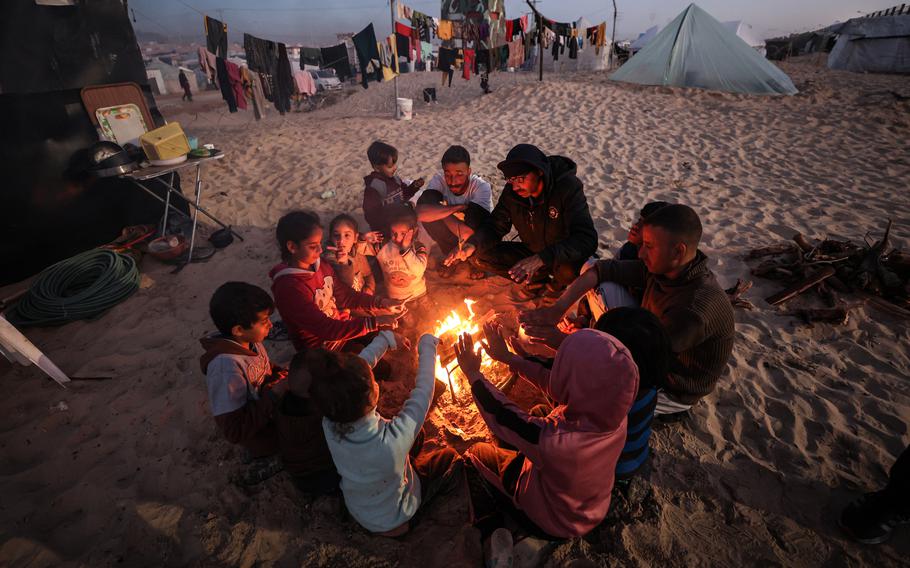A displaced Palestinian family gathers around a fire in a camp for displaced people, south of Rafah on Jan. 21, 2024.
