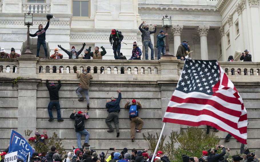 Rioters scale a wall at the U.S. Capitol on Jan. 6, 2021, in Washington.