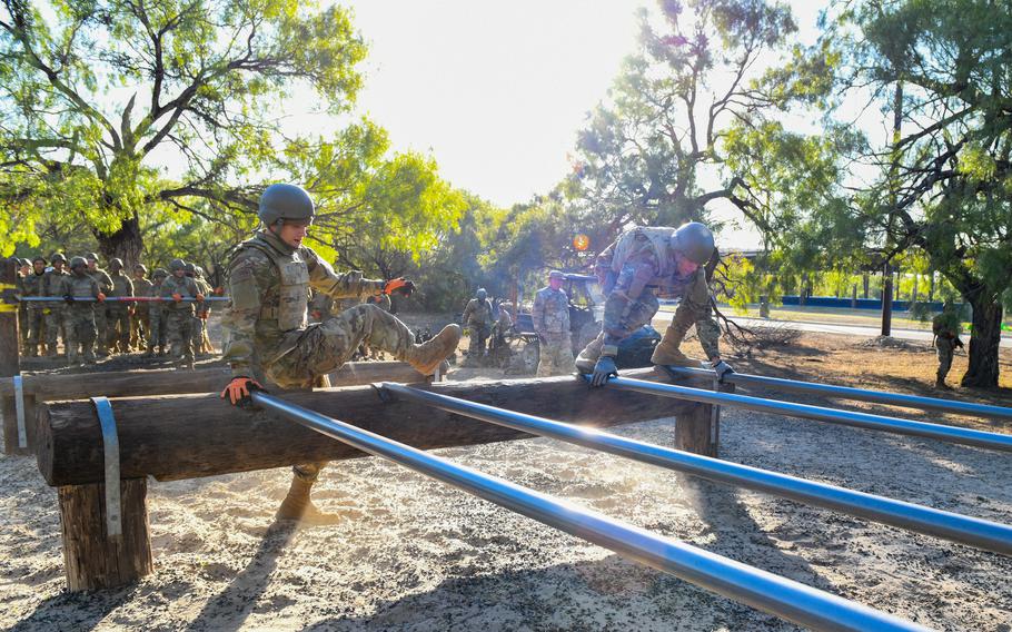 Air Force trainees climb over an obstacle at Joint Base San Antonio-Chapman Training Annex, Texas, on Oct. 26, 2022. Obstacle courses remain part of the new field training portion of Air Force basic training.