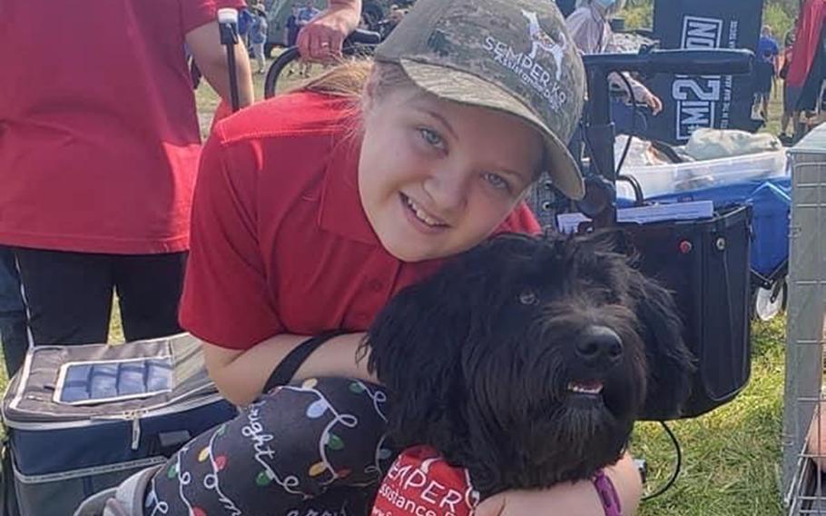 Lily Armstrong poses with Sammy, a service dog she and her family trained for a disabled veteran through Semper K9, a Virginia-based charity that turns rescued dogs into service animals.