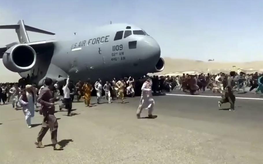Hundreds of people run alongside a U.S. Air Force C-17 transport plane as it moves down a runway of the international airport, in Kabul, Afghanistan, on Monday, Aug. 16, 2021. A member of Afghanistan's national youth soccer team fell from the plane to his death, Afghan officials said Thursday.