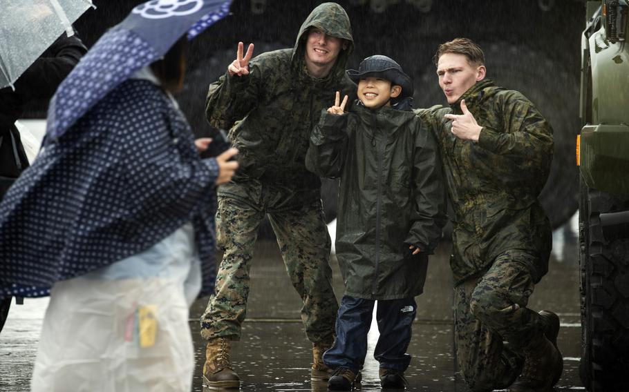 Marine Pfc. David Bello-McCormick, left, and Lance Cpl. Sean Lynch pose with a child at the Friendship Day festival at Marine Corps Air Station Iwakuni, Japan, Saturday, April 15, 2023. 