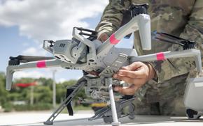 Spc. Michael Fish, an unmanned aerial systems operator with 1st Squadron, 91st Cavalry Regiment, attaches a 3D-printed munitions dropper to a Skydio X10D drone at Grafenwoehr Training Area in Germany on June 25, 2025, during a test in which soldiers dropped live M67 grenades from the drone.
