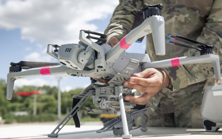 A U.S. soldier attaches a 3D-printed munitions dropper to a drone.