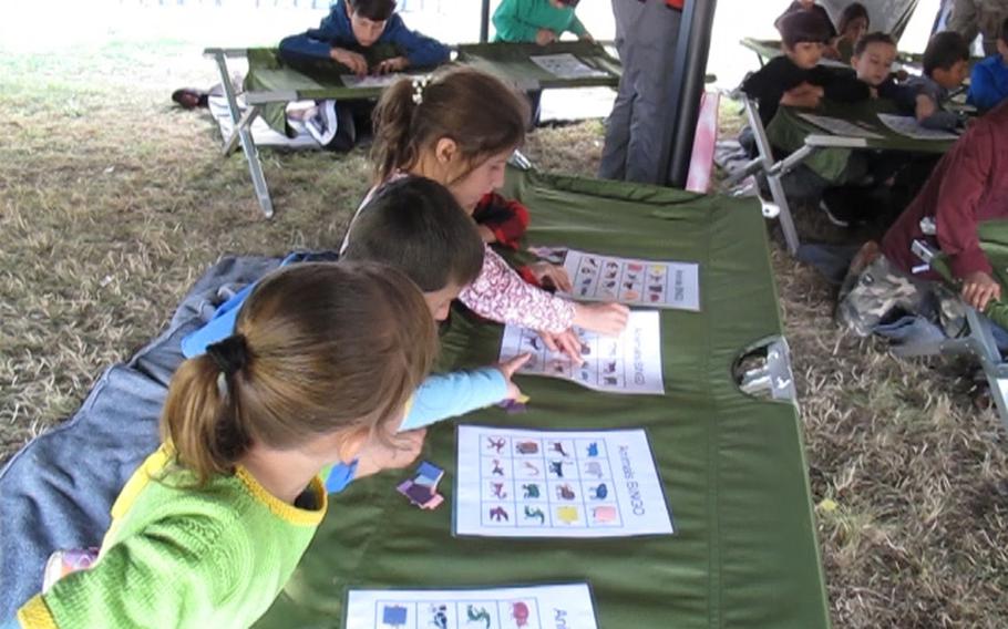 An Afghan girl points to another girl's bingo card during a game hosted by American Red Cross volunteers for refugees who are being temporarily housed at Rhine Ordnance Barracks in Kaiserslautern, Germany, Sept. 24, 2021. 