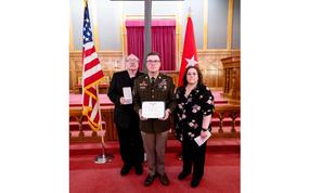 Martin and his parents hold the medals with flags behind them.