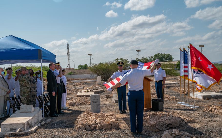 Soldiers assigned to Combined Joint Task Force-Horn of Africa display the American flag at the grave of World War II veteran Arthur Lewis during a burial honors ceremony at the New European Cemetery in Djibouti City, Djibouti, Oct. 28, 2021. Service members cleaned the cemetery and installed a new headstone in honor of Lewis, who died in 1959 while at sea.