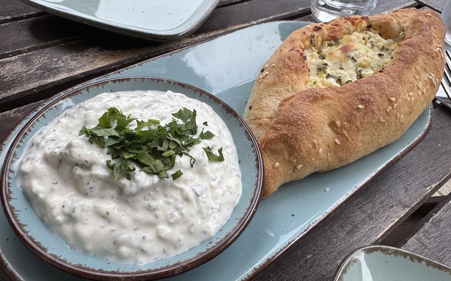 On right, Turkish bread with cheese in the middle, and a yogurt-based sauce with herbs on top on the left