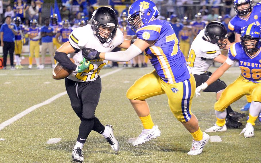 American School In Japan's Noa Grasse has the ball knocked out of his grasp by Yokota's Brailyn Ivey.