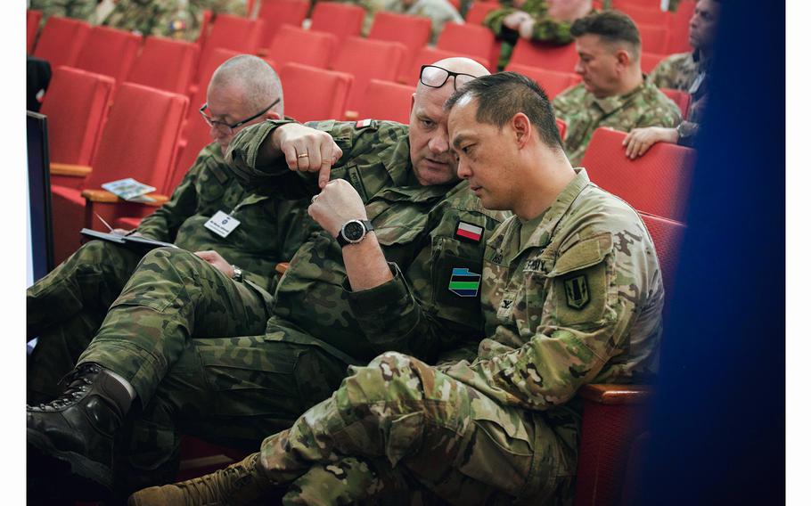 U.S. Army Col. Wilbur Hsu speaks with a Polish soldier during the High Mobility Artillery Rocket System summit in Bucharest, Romania, on Dec. 7, 2023. U.S. Army V Corps troops and counterparts from NATO countries hosted the event, which was dedicated to HIMARS capabilities.