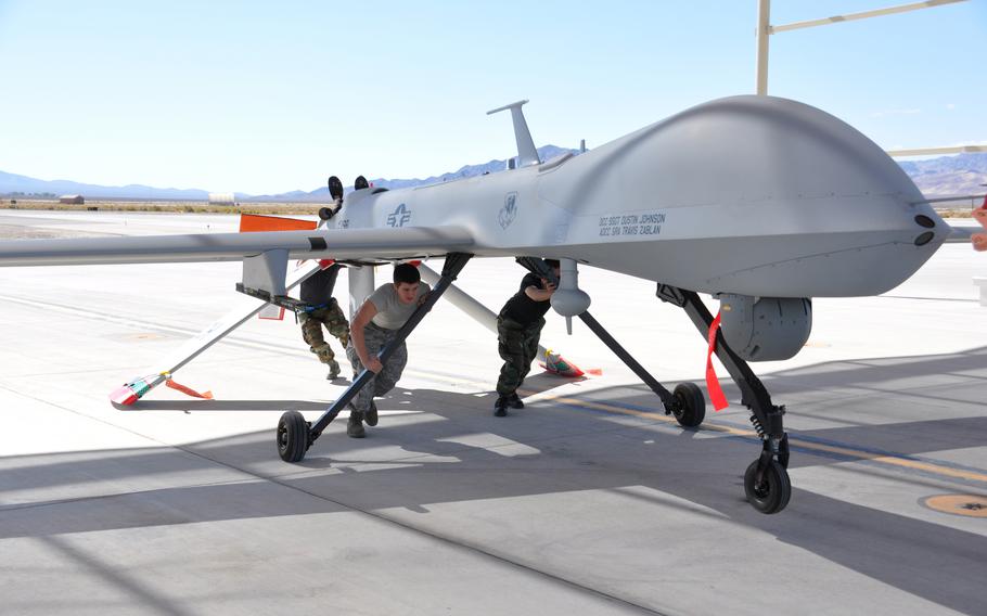 Airmen at Creech Air Force Base, Nev., push a Predator drone back to the hanger for maintenance
