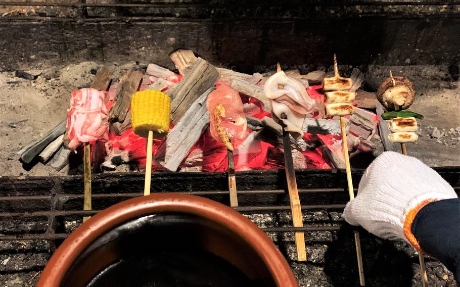 Diners grill their own skewers over a hot bed of coals at Sanrokuen in Kawaguchiko, Japan. They can dip the skewers into a large jar of tare, or sauce.